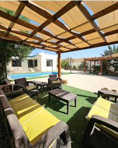 a patio with tables and chairs under a wooden pergola at Shamsa Chalet in Al Mazār