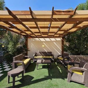 a patio with chairs and a wooden pergola at Shamsa Chalet in Al Mazār +3 photos
