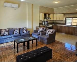 a living room with couches and a table and a kitchen at Shamsa Chalet in Al Mazār
