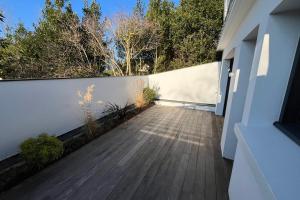 a balcony with a wooden floor and a white fence at Maison proche grande plage in Quiberon
