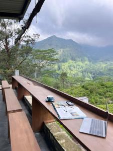 a table with a laptop and a book on it at Misty mountains residents in Huluganga