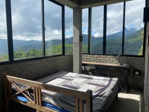 a room with a bed and a table and windows at Misty mountains residents in Huluganga