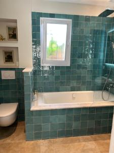a green tiled bathroom with a tub and a window at Chambre Villa piscine in Saint-Tropez +4 photos