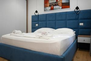 a bed with a blue headboard with towels on it at Blue Heaven Seaside in Borsh