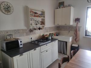 a kitchen with white cabinets and a microwave and a sink at Dal Grof in Tualis