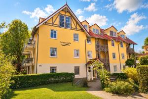 a large yellow building with a red roof at Apartmenthaus Ostseewelle Ferienwohnung 13 in Kühlungsborn