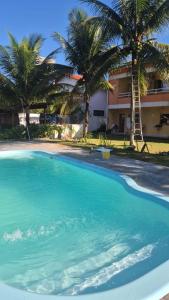 a large swimming pool with palm trees in the background at Pousada Elshadai in Uruçuca