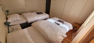 three beds in a room with white sheets at Nord Hus 3 in Loppa