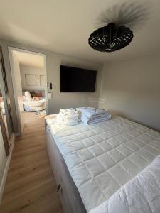 ein Schlafzimmer mit einem großen weißen Bett und einem Flachbildfernseher in der Unterkunft It Paradys in Dronrijp