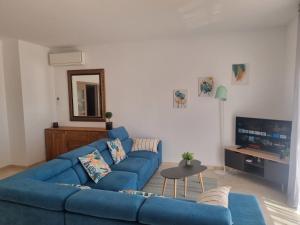 a living room with a blue couch and a tv at villa piscina y vistas espectaculares a la montana , gran terraza y aire acondicionado in Cuevas del Almanzora