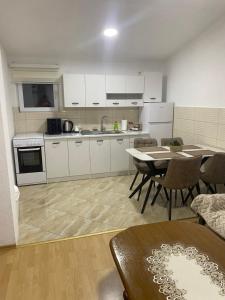 a kitchen with white cabinets and a table and chairs at Rena Comfort Apartment in Bar