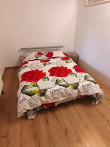 a bed with a quilt with red roses on it at Motoráj -apart Kutná Hora in Kutná Hora