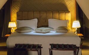 a bedroom with a large white bed with two lamps at Posho Sunset Mara in Sekenani +4 photos