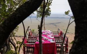 a table with a red table cloth and chairs with a view at Posho Sunset Mara in Sekenani