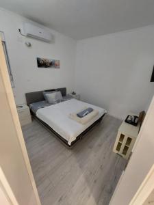 a white bedroom with a bed and a wooden floor at Rooms By the way M17 in Vrapčići
