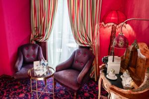 a pink room with two chairs and a table and a mirror at La Villa Royale in Paris