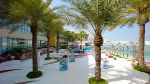 a resort with palm trees and a swimming pool at Dragon Beach Hotel in Manama