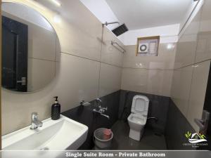 a bathroom with a sink and a toilet and a mirror at Greenleaf Holidays in Munnar +33 photos
