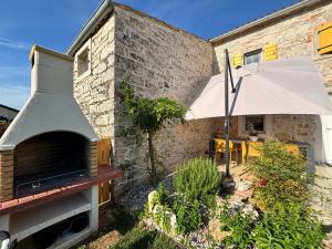 a brick building with a pizza oven and an umbrella at Casa Viva in Umag