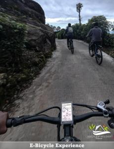 two people riding bikes on a dirt road at Greenleaf Holidays in Munnar