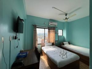 a room with two beds and a television in it at Hotel Majesty Katari in Tribeni Ghāt