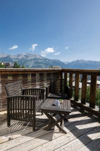 two benches and a table on a deck with mountains at Beau studio Pra loup 1500 in Pra-Loup