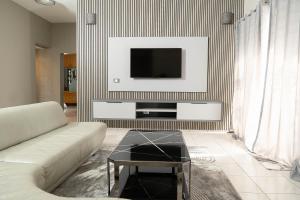 a living room with a couch and a tv on a wall at 157 on North-Sandton in Johannesburg