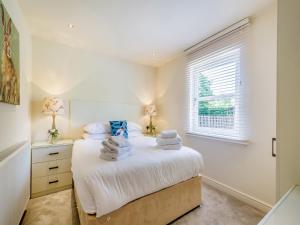 a white bedroom with a bed and a window at Duck Bay Cottage 2 - Uk43935 in Balloch +13 photos