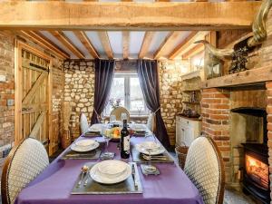 a dining room with a table and a fireplace at Honey Pots in Foulden