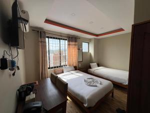 a room with two beds and a table and a window at Hotel Majesty Katari in Tribeni Ghāt