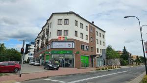 a building on the corner of a street with cars parked at Płock City Center Apartment in Płock
