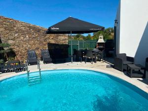 a swimming pool with chairs and an umbrella at Casa dos Avós in São Brás de Alportel