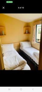 two beds in a small room with a window at Caravan 63 Fishguard Holiday Park in Fishguard