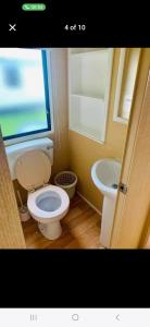 a bathroom with a toilet and a sink and a window at Caravan 63 Fishguard Holiday Park in Fishguard