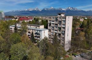 an apartment building with snow covered mountains in the background at Apartmán KUVIK in Poprad