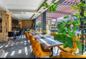 a restaurant with wooden tables and chairs and plants at Galerija Odzaci in Odžaci