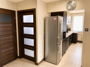 a kitchen with a refrigerator and a clock on the wall at BAIO Apart Sapphire in Libiąż +22 photos
