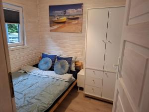 a small bedroom with a bed with blue pillows at Domek nad morzem 79 in Stegna