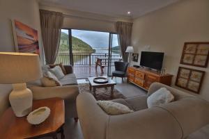 a living room with couches and a television and a balcony at Igoda Mouth Resort in Winterstrand
