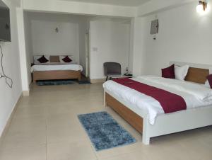 a bedroom with two beds and a chair in it at Vybent hotel kainchi dham in Bhowāli