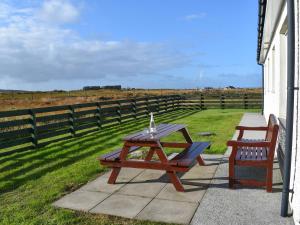 a picnic table and a chair on a patio with a field at Lochboisdale Cottage in Lochboisdale