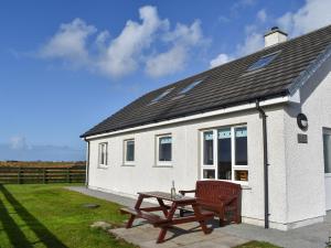 a white house with a picnic table in front of it at Lochboisdale Cottage in Lochboisdale