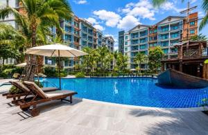 a pool at a resort with chairs and an umbrella at The Title Residencies Naiyang in Phuket