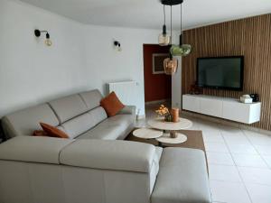 a living room with a white couch and a tv at A Beloeil, On Vous Acceuille in Beloeil