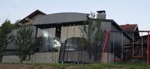 a glass extension of a house with a tree at Vikendica Tuzla baracuda bazen in Slavinovići