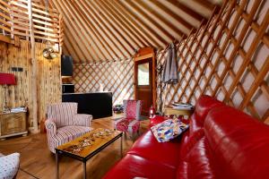 a living room with a red leather couch and chairs at Les Yourtes de La Valette in Floreffe