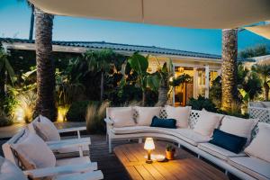 a patio with white furniture and palm trees at Epi Baie de Pampelonne in Saint-Tropez
