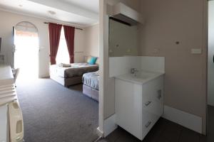 a bathroom with a sink and a bedroom with two beds at The Argent Motel in Broken Hill