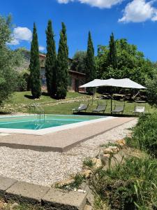 a swimming pool with two chairs and an umbrella at sacrobosco Country House in Porchiano
