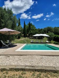 a swimming pool with an umbrella and two chairs and a table at sacrobosco Country House in Porchiano